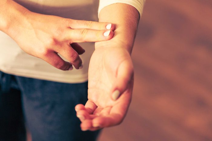 Woman checking her pulse with two fingers.