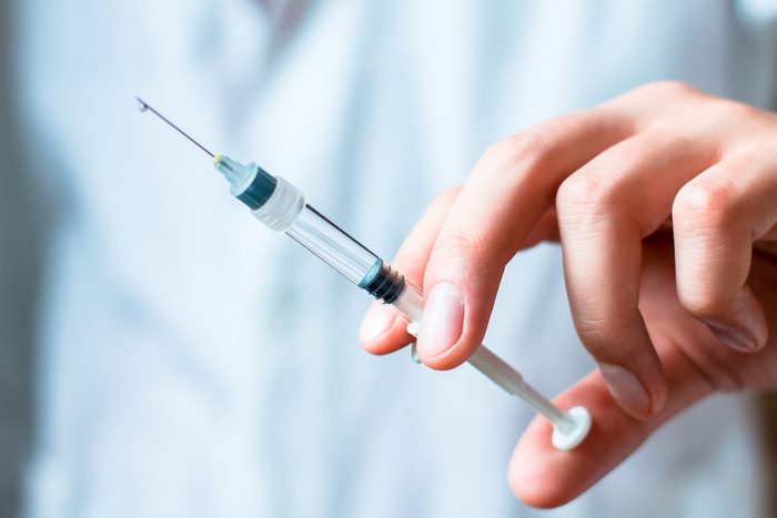 Syringe, medical injection in hand, palm or fingers. Medicine plastic vaccination equipment with needle. Nurse or doctor. Liquid drug or narcotic. Health care in hospital.