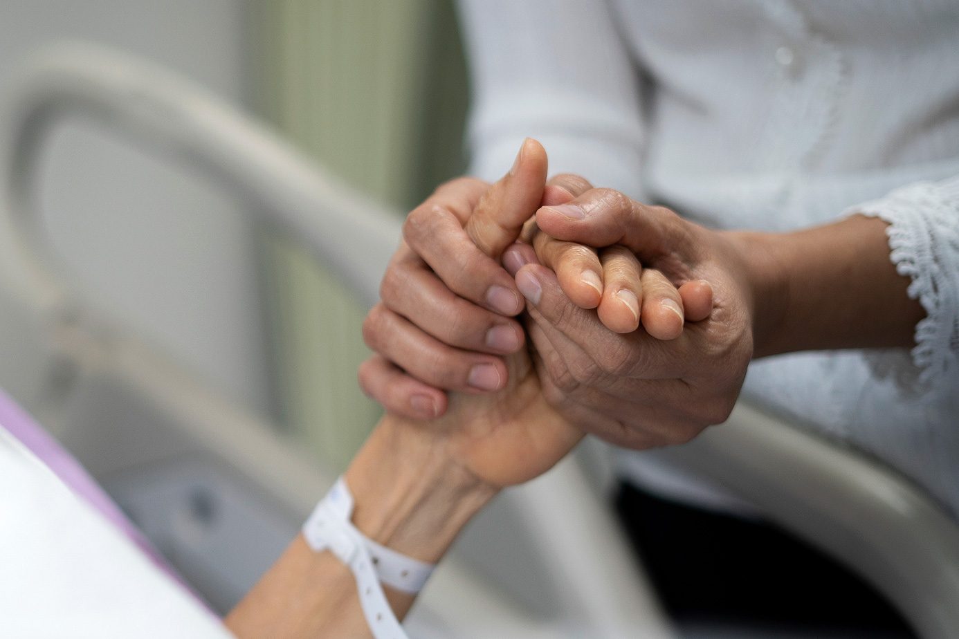 Shot of daughter encourage her mother and holding the mother's hand to sleep on the bed ​in hospital.