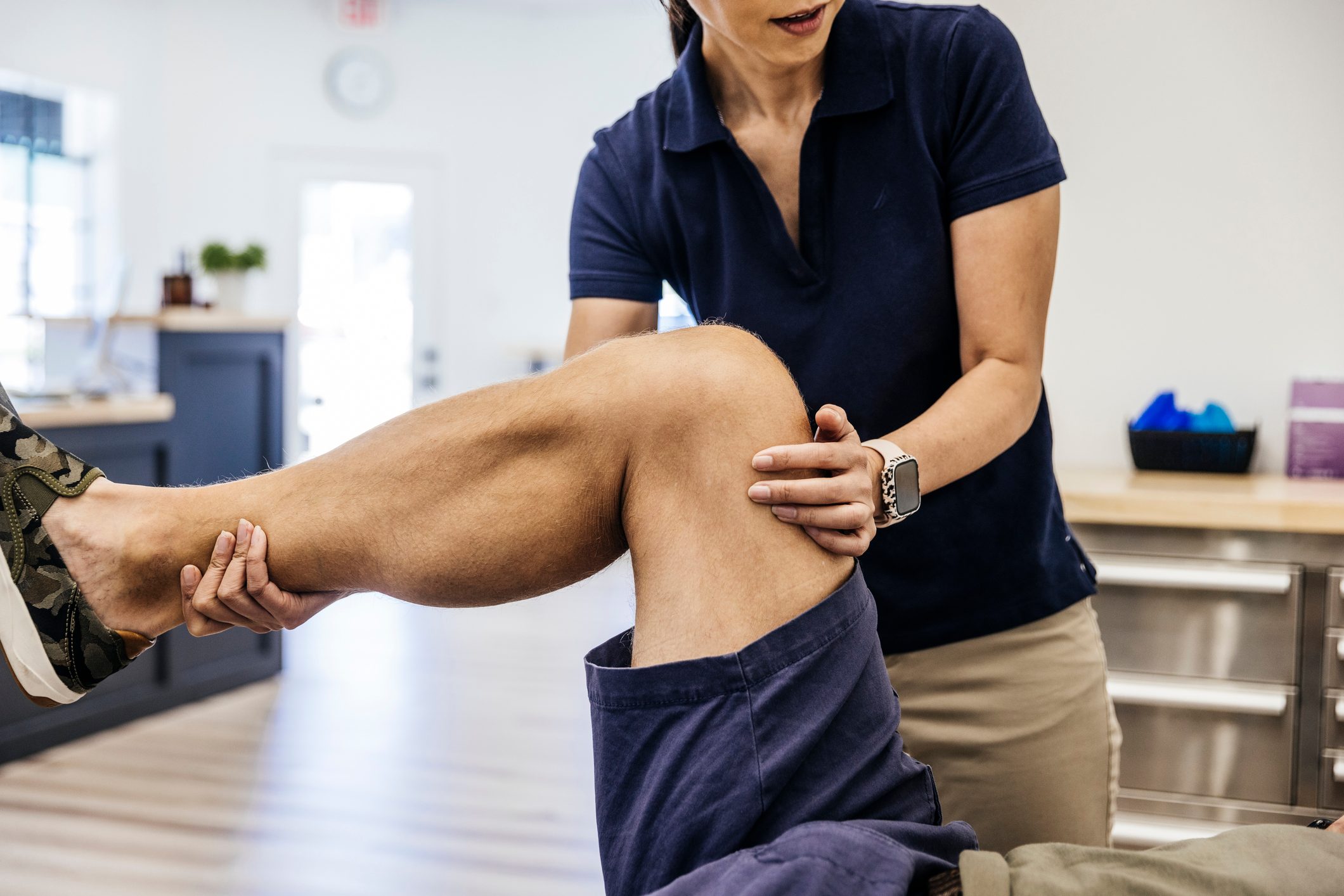 Physical therapist stretching knee of male patient